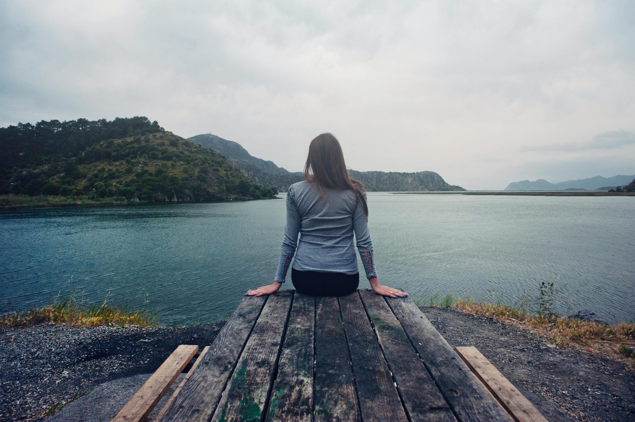 A person sat near the river.